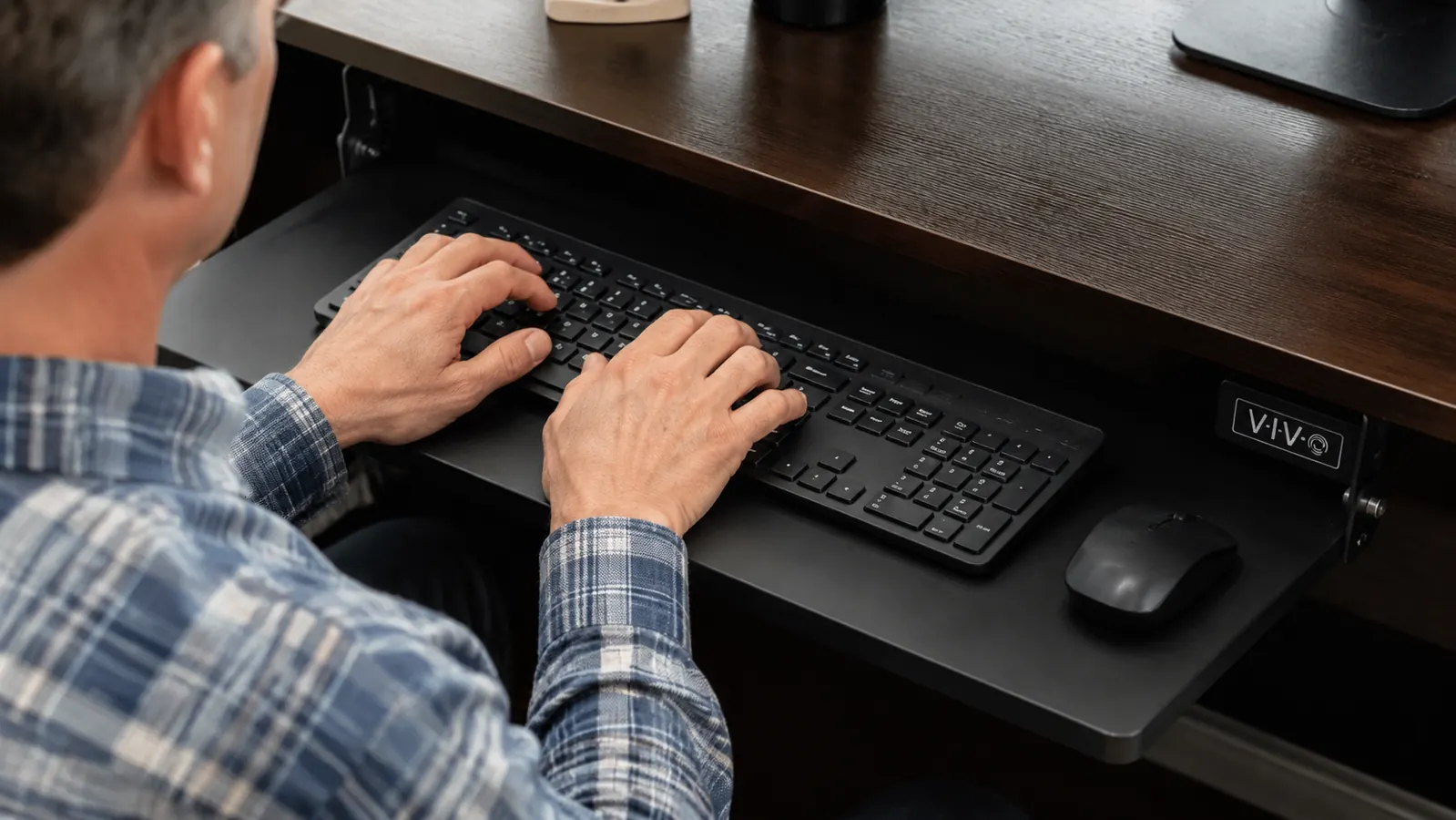 Close-up of hands typing on a keyboard resting on a slide-out under-desk tray, wrists in a flat neutral position