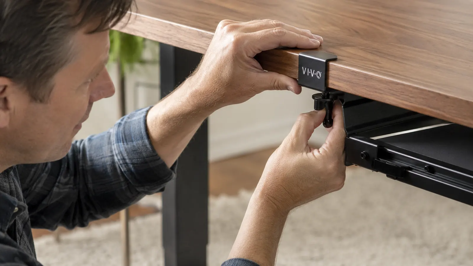 Hand tightening the C-clamp mounting bracket of the VIVO keyboard tray underneath a desk edge